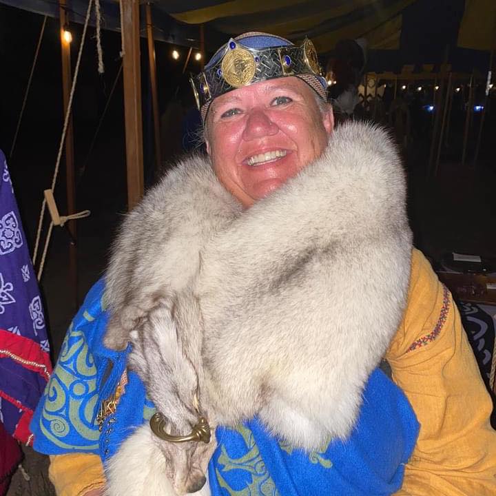 One of the three event stewards, Thyri ingen Aedain ui Rigain, smiling while wearing their regalia and furs. Contact this coordinator.